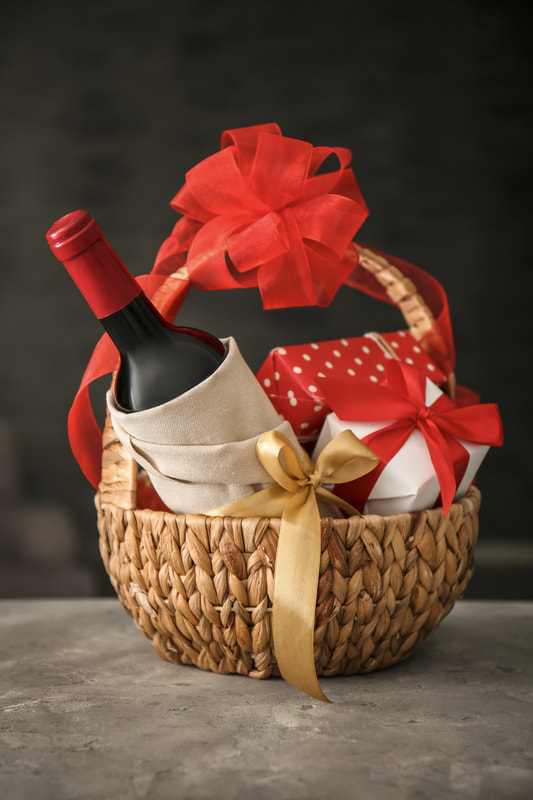 Gift basket with a bottle of wine and wrapped presents tied with red ribbon (stock photo)